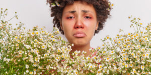 woman-surrounded-by-camomile-flowers-has-red-swollen-eye-srunny-nose-suffers-from-seasonal-pollen-allergy-needs-consultancy-immunologist